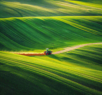 农田庄稼里耕种的机器农忙劳动节摄影图