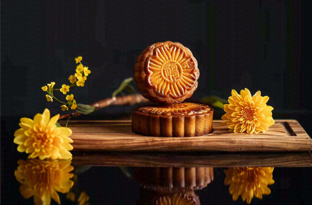 中国传统美食月饼中秋节菊花摆盘黑色背景摄影图
