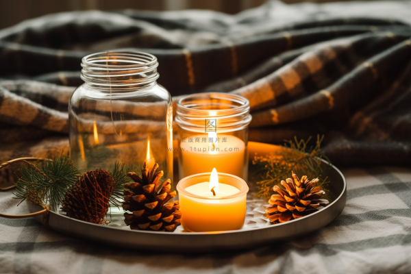 秋冬房间茶几托盘里点燃的香薰杯蜡烛松果玻璃瓶摄影图