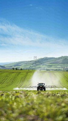农田庄稼里耕种的机器农忙劳动节摄影图