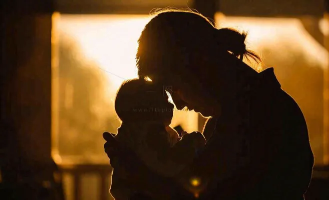 母亲节晚霞光辉妈妈抱着孩子摄影图