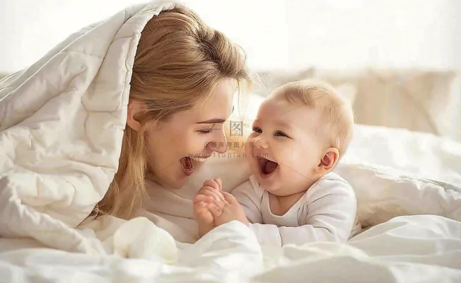 妈妈陪着婴儿玩耍白色床温馨母亲节摄影图