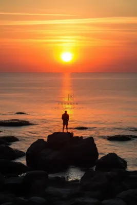 站在礁石上观赏落日的人落日余晖倒影摄影图