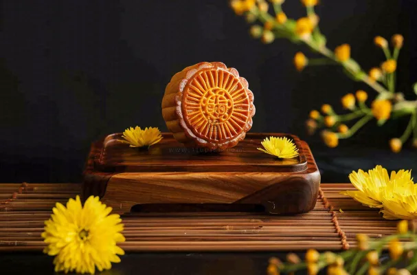 中国传统美食月饼中秋节菊花摆盘黑色背景摄影图