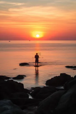 站在礁石上观赏落日的人落日余晖倒影摄影图