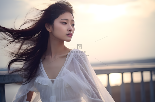 一个美女穿着一件漂亮的白色连衣裙在海边的拍照摄影图