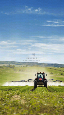 农田庄稼里耕种的机器农忙劳动节摄影图